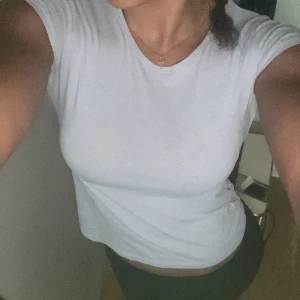 Vit basic t-shirt från H&M - Enkel och fräsch vit t-shirt från H&M Basic i ekologisk bomull. Modellen är klassisk med rund halsringning och korta ärmar. Perfekt till jeans eller shorts för en clean och stilren look. 