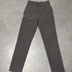 Grå kostymbyxor från Gina Tricot XS - Snygga grå kostymbyxor från Gina Tricot i storlek XS. Byxorna har hög midja, raka ben och diskreta fickor framtill. Perfekta för en clean och stilren look. Materialet känns mjukt och följsamt.