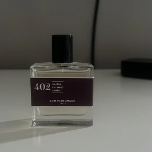Bon Parfumeur 402 Vanilj & Karamell - Parfymflaska från Bon Parfumeur, doft 402 med noter av vanilj, karamell och sandelträ. Flaskan är rektangulär i genomskinligt glas med svart lock och mörklila etikett. En söt och varm doft. Gillar du gourmand kommer du älska denna!