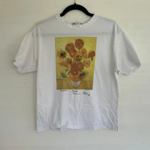Vit t-shirt med tryck - Vit t-shirt från Zara med ikoniskt Van Gogh Sunflowers-tryck på bröstet. Klassisk passform, rund hals och korta ärmar. Mjuk bomullskvalitet som är skön att bära. Perfekt för dig som gillar konst och vill ha en chill vibe i din outfit.