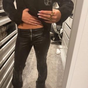 Svarta skinnbyxor från Gina Tricot - Snygga svarta skinnbyxor från Gina Tricot, bootcut och låg midja. Byxorna har dragkedja framtill. Används 2 gånger