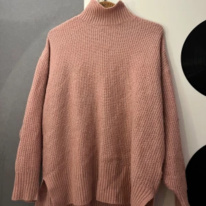 Rosa stickad polotröja från H&M - Mysig rosa stickad polotröja från H&M i storlek L. Tröjan har en hög polokrage, lång ärm och ribbade muddar samt nederkant. Perfekt för lager-på-lager och chill höst- och vinterstil.