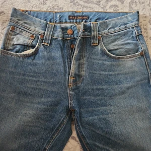 Nudie Jeans Steady Eddie Blue Water 29/32 - Snygga blå Steady Eddie jeans från Nudie Jeans i modellen Blue Water. Tillverkade av 100% ekologisk bomull med klassisk femficksdesign, orange kontrastsömmar och ikonisk brodering på bakfickorna.