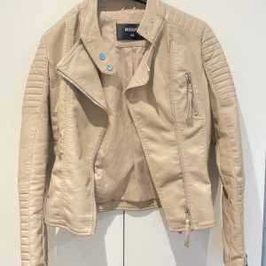 Beige skinnjacka från Missäy - Snygg beige skinnjacka från Missäy i storlek XS. Ganska tajt i modellen. Köpt för 499kr, säljs för 199kr. Nästintill oanvänd, endast vid 2-3 tillfällen ungefär. Köparen står för frakten! 