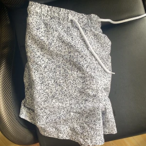 Vita och svarta badshorts från SURF - Snygga vita badshorts från SURF i storlek medium med svart prickigt mönster. Shortsen har elastisk midja med vit snörning och innerfoder i mesh. Perfekta för stranden eller poolen, riktigt fräsch look till sommaren.