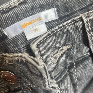 Grå bootcut jeans från Gina Tricot - Snygga grå jeans från Gina Tricot i bootcut-modell. Jeansen har klassisk femficksdesign, dragkedja och knapp framtill. Materialet är jeans med en tvättad grå nyans som ger en cool vibe. Perfekta för dig som gillar en trendig och avslappnad stil. Str 170, skriv för fler bilder och frågor💕