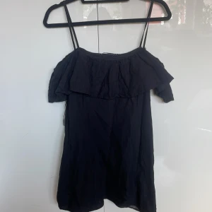 Svart off shoulder klänning - Säljer en svart kort klänning från Zara med smala axelband, volang upptill och som är off shoulder. Passar mig som egentligen är storlek S men säljer då den är för kort💕😁