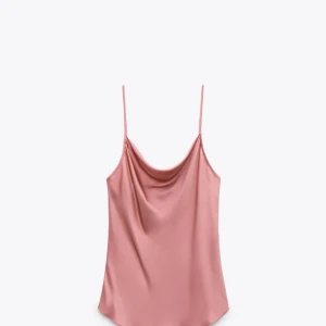 Rosa silkes linne med smala axelband från Zara - Säljer ett rosa linne från Zara, materialet är i silke och den har smala axelband. Linnet har är mjuk och glansig. Den är i stolek XS och har aldrig använts. 