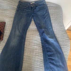 Levi's 479 Booty Flare Fit jeans LÅGMIDJADE - Säljer ett par klassiska blå Levi's 479 Booty Flare Fit jeans med utsvängda ben och femficksmodell. Jeansen har orangea sömmar och normal passform med flare-stil. Perfekta för dig som gillar retrovibbar och snygg siluett. LÅGMIDJADE. MIDJEMÅTT: 34/36 cm skulle jag säga. INNERBENSLÄNGD: 72cm