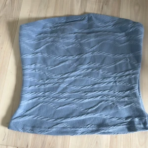 Ljusblå tubtopp från SHEIN - Säljer en ljusblå tubtopp från SHEIN. Toppen har ett diskret vågigt mönster i tyget och är tillverkad i ett mjukt material. Perfekt för varma dagar eller som layering-plagg. Toppen är liten i storlek, känns mer som en xs än s.