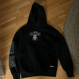 Svart hoodie La Casa de Papel x Pull&Bear - Säljer en svart hoodie från Pull&Bear i samarbete med La Casa de Papel. Tryck med Bella Ciao och Money Heist-motiv både fram och bak. Stor ficka framtill och huva. Perfekt för fans av serien!