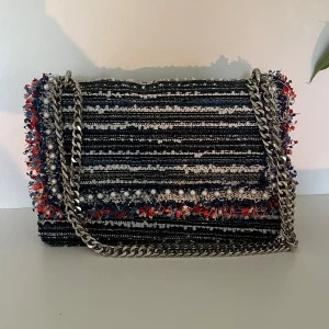 Väska Zara - Säljer denna snygga unika väskan från Zara, randigt mönster med lite fransar och silverfärgad kedja. Perfekt för att lyfta vilken basic outfit som helst. Inga tecken på användning💞