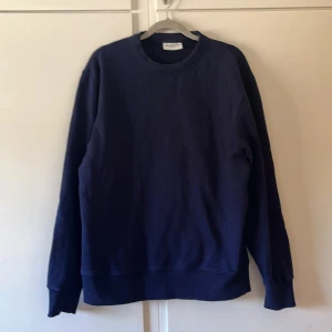 Mörkblå sweatshirt från These Glory Days - En stilren mörkblå sweatshirt från These Glory Days. Tröjan har rund halsringning och ribbade muddar vid ärmslut och nederkant. Inga defekter.