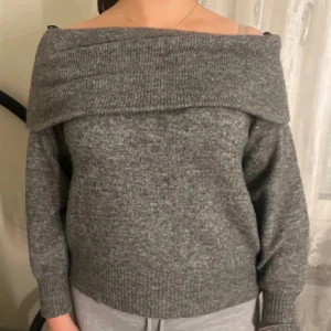 Grå offshoulder stickad tröja - Säljer en grå stickad tröja med bred offshoulder-krage. Tröjan har lång ärm och ribbade muddar vid ärmslut och nederkant. Skriv för fler bilder och pris kan diskuteras💕💕