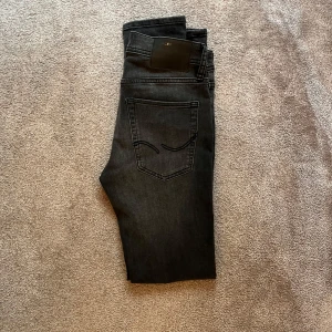 Grå Jack and Jones jeans  - Säljer ett par grå  jeans från Jack and Jones. Jeansen är i väldigt bra skick och har ett sjukt bra pris. Storlek W27/L32.