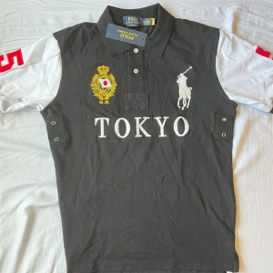 Chief keef polo Tokyo - Säljer en svart och vit pikétröja från Polo Ralph Lauren med stora broderade detaljer, Tokyo-tryck och siffran 5 i rött på ryggen. Klassisk krage och korta ärmar, perfekt för en sportig look.