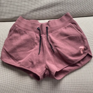 Rosa shorts från Peak Performance (ny skick) - Mysiga rosa shorts från Peak Performance med bred resår i midjan och svarta snören. Modellen har två fickor fram och en liten logga på ena benet. Perfekta för avslappnade dagar eller träning. (För små för mig)
