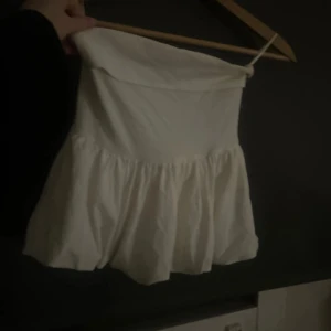 Vit axelbandslös volangtopp - Säljer en söt vit axelbandslös topp med volang nertill.  Perfekt för sommaren eller som en söt fest topp💓🤗