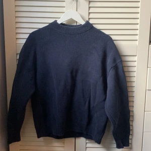 Mörkblå stickad tröja från Weekday - Säljer en mörkblå stickad tröja från Weekday i oversized modell. Tröjan har rund halsringning och långa ärmar, perfekt för lager-på-lager. Enkel och stilren design som passar till det mesta.