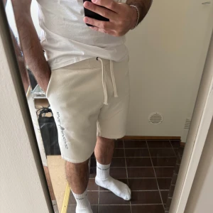 Vita shorts från Sail Racing med snörning - Snygga vita shorts från Sail Racing med broderad logga på vänster ben. De har en normal passform och är utrustade med snörning i midjan för bästa komfort. Perfekta för sommaren och tillverkade i mjuk bomull.