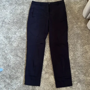 Mörkblåa kostymbyxor - Snygga mörkblåa kostymbyxor från STOCKH LM med klassisk rak passform och diskreta fickor i sidorna. Perfekta för en stilren look och passar till många olika outfits.