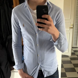 Blåvit randig skjorta från Ralph Lauren - Säljer en slim fit skjorta från Ralph Lauren i blåvitt randigt mönster. En perfekt skjorta för en sommardag. Hör bara av dig vid någon fråga
