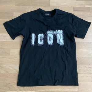 Svart t-shirt från Dsquared2 med tryck - Säljer en svart t-shirt från Dsquared2 med stort vitt 'ICON'-tryck på bröstet. Klassisk passform och rund halsringning. Perfekt för dig som gillar streetwear och vill sticka ut med en ikonisk look. Pris kan diskuteras 😃