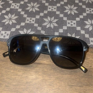 Svarta solglasögon från Dior Homme - Snygga svarta solglasögon från Dior Homme med fyrkantig form och diskret textur på bågarna. Märkt med 'CD' på sidan och modellen heter Blacktie 165S. Tillverkade i Italien, passar perfekt för dig som gillar stilrena accessoarer. Köpta från NK för många år sedan. Inget kvitto.