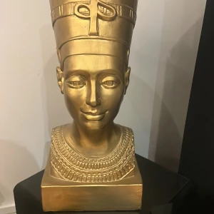Guldfärgad egyptisk krona.  - Säljer en ikonisk guldfärgad huvudbonad inspirerad av forntida Egypten, med hög cylinderform och detaljerade band runt om. Perfekt för dig som vill sticka ut med en unik och historisk look.