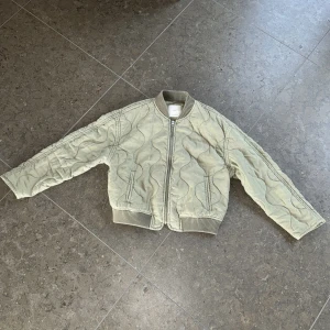 Grön quiltad vårjacka från MNG stl S/M - Säljer en ljusgrön quiltad bomberjacka från MNG/Mango med dragkedja framtill och ribbade muddar vid krage, ärmslut och nederkant. Sliten look som är original från början (alltså ej urtvättad). Storlek M men är liten i storleken och använd av en normal S. Mjukt skönt material och använd endast ett fåtal gånger.  