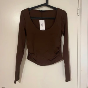 Brun långärmad topp från Stradivarius - Säljer en brun långärmad topp från Stradivarius med rundad urringning. Toppen har en tight passform och är tillverkad i ett mjukt, stretchigt material. Perfekt att styla med jeans eller kjol.