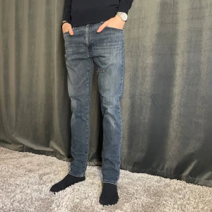 Blå jeans från Levi's - Säljer ett par klassiska blå jeans från Levi's med slim passform. Jeansen har normal midja och subtila slitningar på framsidan för en avslappnad look. Perfekta till vardags och passar till det mesta. OBS! Jeansen är små i midjan. Skick 8/10✅ Pris kan diskuteras vid snabb affär💸