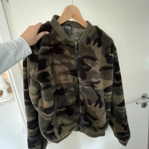 Camouflage teddyjacka med dragkedja - Säljer en mjuk supercool teddyjacka i camouflage-mönster. Jackan har dragkedja framtill, ribbade muddar och krage. Perfekt för dig som vill ha en skön jacka nu till våren och sommaren! Hör av er vid frågor 🥰