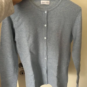 Ljusblå kofta från Davida - Säljer en superfin ljusblå kashmir kofta från Davida med rund halsringning och knappar framtill. Enkel och stilren design som passar till allt! Hör av er vid frågor 🥰