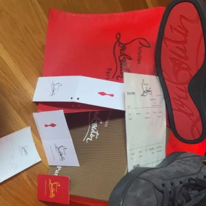 Gråa sneakers från Christian Louboutin - Säljer ett par gråa sneakers från Christian Louboutin med klassisk röd sula och snörning. Skorna är i mocka och har en rund tå. Kommer med originalkartong och tillbehör. Vid snabb affär kan vi gå ner i pris! Inga skambud.
