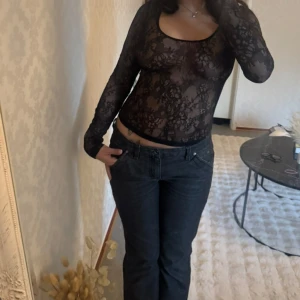 Svart spetstopp  - Svart spetstopp med lång ärm och rundad urringning.  Toppen är tight och har ett blommigt spetsmönster. 