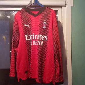 AC Milan långärmad fotbollströja från Puma *äkta - Säljer en röd och svart långärmad AC Milan fotbollströja från Puma med klubbmärke och sponsortryck på bröstet. Tröjan har ett mönster av svarta linjer och V-ringad krage. Perfekt för fotbollfans tröjan är använd typ 1 gång och den är äkta Köptes på en puma butik pris går att diskutera 