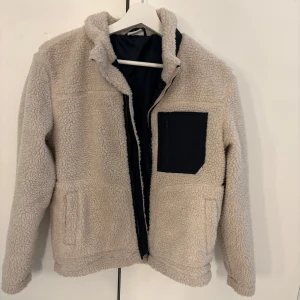 Teddyjacka - Säljer min beiga trddyjacka med svarta detaljer då den inte kommer till användning, använd ca 5 ggr så väldigt fint skick, storlek L men skulle säga att den sitter som en S