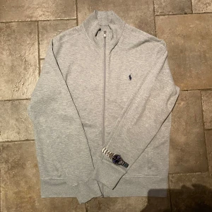 Ralph Lauren Full Zip Large - Grå Ralph Lauren Full Zip tröja med klassisk mörkblå häst. 100% äkta och i nästintill nyskick. Enda defekten är texten i nacken som blivit borttvättad. 