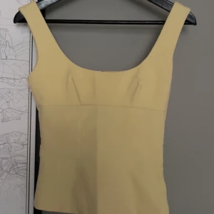 söt topp - Säljer en ljusgul linnetopp från H&M med breda axelband och fyrkantig ringning. Toppen är enkel och stilren, perfekt att matcha med jeans eller kjol. Materialet känns mjukt och lätt mot huden. helt slutsåld på hemsidan 🥰