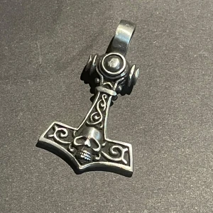 Silverfärgat Thorshammare-halsband - Halsband i form av Thors hammare med detaljerade mönster och en dödskalle framtill. Gjord i silverfärgad metall med antik finish och ögla för kedja. Perfekt för dig som gillar nordisk mytologi. 