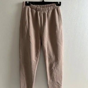 Ljusbruna mjukisbyxor med resår - Säljer ett par bruna mjukisbyxor med resår i midjan och vid bensluten. Byxorna har en avslappnad passform och är gjorda i mjukt bomullsmaterial, perfekta för chill dagar eller när du vill vara extra bekväm.
