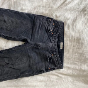 Svarta jeansbyxor från Gina Tricot  - Säljer ett par svarta jeansbyxor från Gina Tricot med klassisk femficksdesign och raka ben. Byxorna har knapp- och dragkedjegylf samt detaljer i kopparfärg. Perfekta till vardags och enkla att matcha.