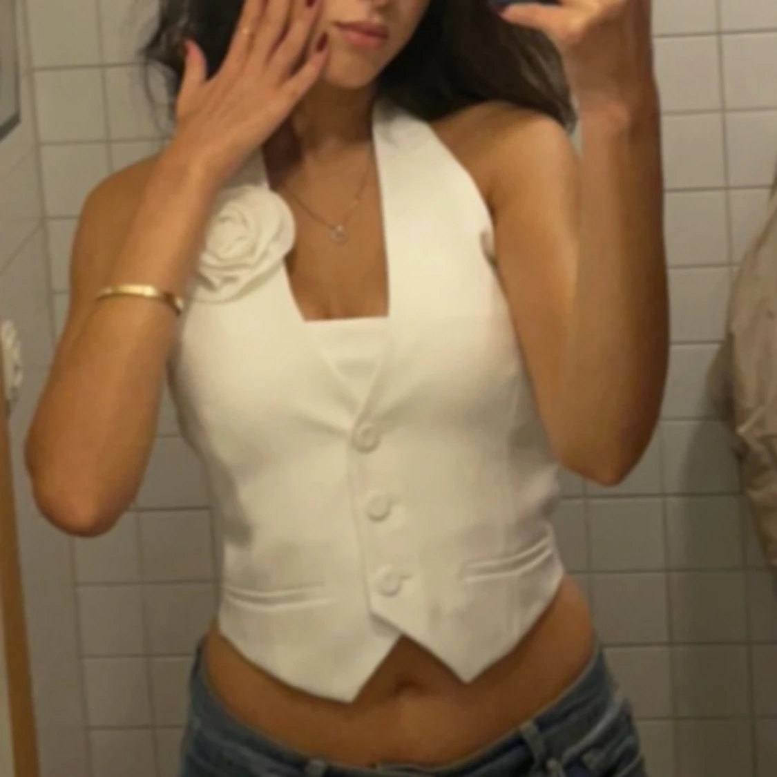 Vit halterneck väst med blomdetalj