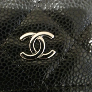 Wallet on chain  - Säljer en klassisk svart axelväska quiltat skinn med silverfärgad kedja och CC-logga framtill. Väskan har flera fack, innerfoder i mörkbrunt tyg och en praktisk ficka på baksidan. 10A, kommer med box, dustbag och kort