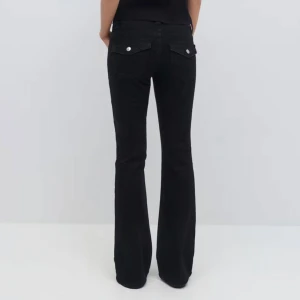 Svarta bootcut jeansbyxor - Svarta jeansbyxor med bootcut passform och klassiska fickor bak med lock och knappar. Bra skick!!