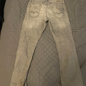 Ljusgrå jeansbyxor från Replay - Säljer ett par ljusgrå jeansbyxor från Replay med slim fit. Byxorna har diskreta slitningar och tydliga sömmar på bakfickorna. Perfekta för dig som gillar en stilren och avslappnad look.storlek W31 L32