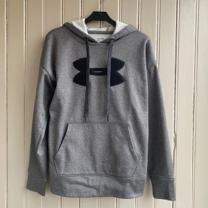 Under Armour hoodie - En Under Armour hoodie i ett väldigt fint skick skulle säga att den är som ny. Storleken säger XS men jag skulle säga att den är mer av en S storlek.   På den sista bilden kan du se hur den ser ut på mig som är 175 cm. Måtten är ca 65 i längd och 40 i axelbredd.   Tveka inte på att skriva om du har några frågor!💬 