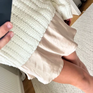 Beige kortkjol i satin - Säljer en beige kortkjol i satin med lätt glansig yta och mjukt fall. Kjolen har en enkel och stilren design utan synliga detaljer och sitter normalt i midjan. 🩷