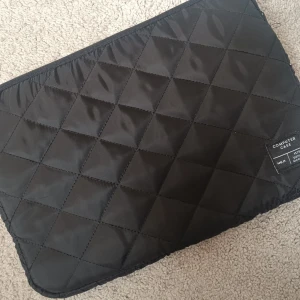 Svart datorväska / datorfodral  - Säljer en svart datorväska/datorfodral från lager 157. Väskan har ett stilrent rutmönster och är vadderad för extra skydd. Perfekt för att bära med sig laptopen till skolan eller jobbet. Aldrig använd då jag köpte ett förlitet fodral!! 15 kronor 